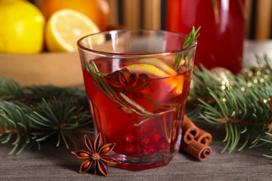 Photo of Aromatic punch drink and fir tree branch on wooden table, closeup