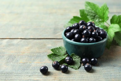 Photo of Ripe blackcurrants and leaves on wooden rustic table. Space for text