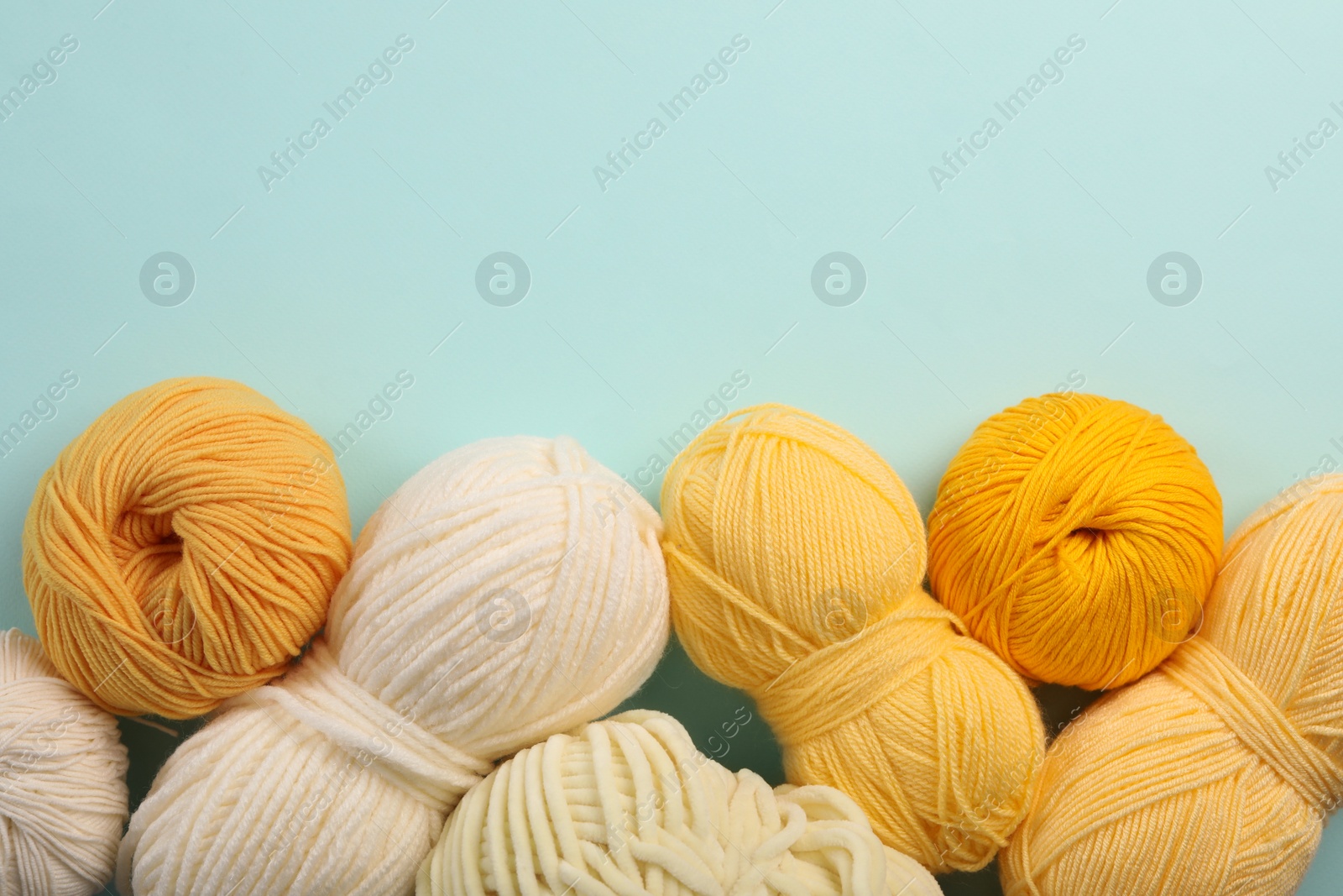Photo of Soft woolen yarns on light blue background, flat lay. Space for text