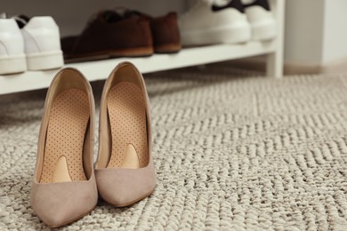 Photo of Orthopedic insoles in high heel shoes on rug. Space for text