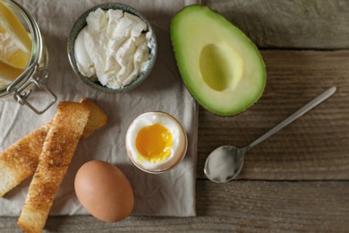 Photo of Soft boiled egg served for breakfast on wooden table, flat lay
