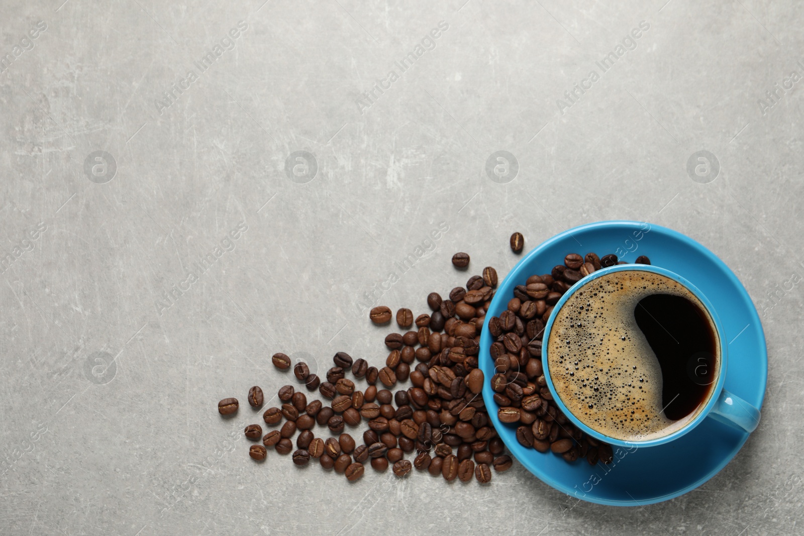 Photo of Cup of aromatic coffee and beans on light grey table, flat lay. Space for text