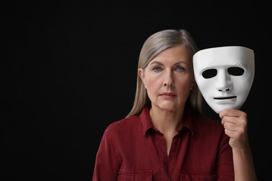 Photo of Multiple personality concept. Woman with mask on black background, space for text
