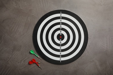 Photo of Dart board with color arrows on grey stone background, top view
