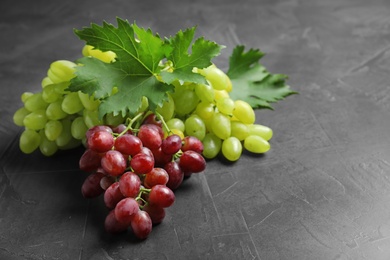 Photo of Fresh ripe juicy grapes on grey table, space for text