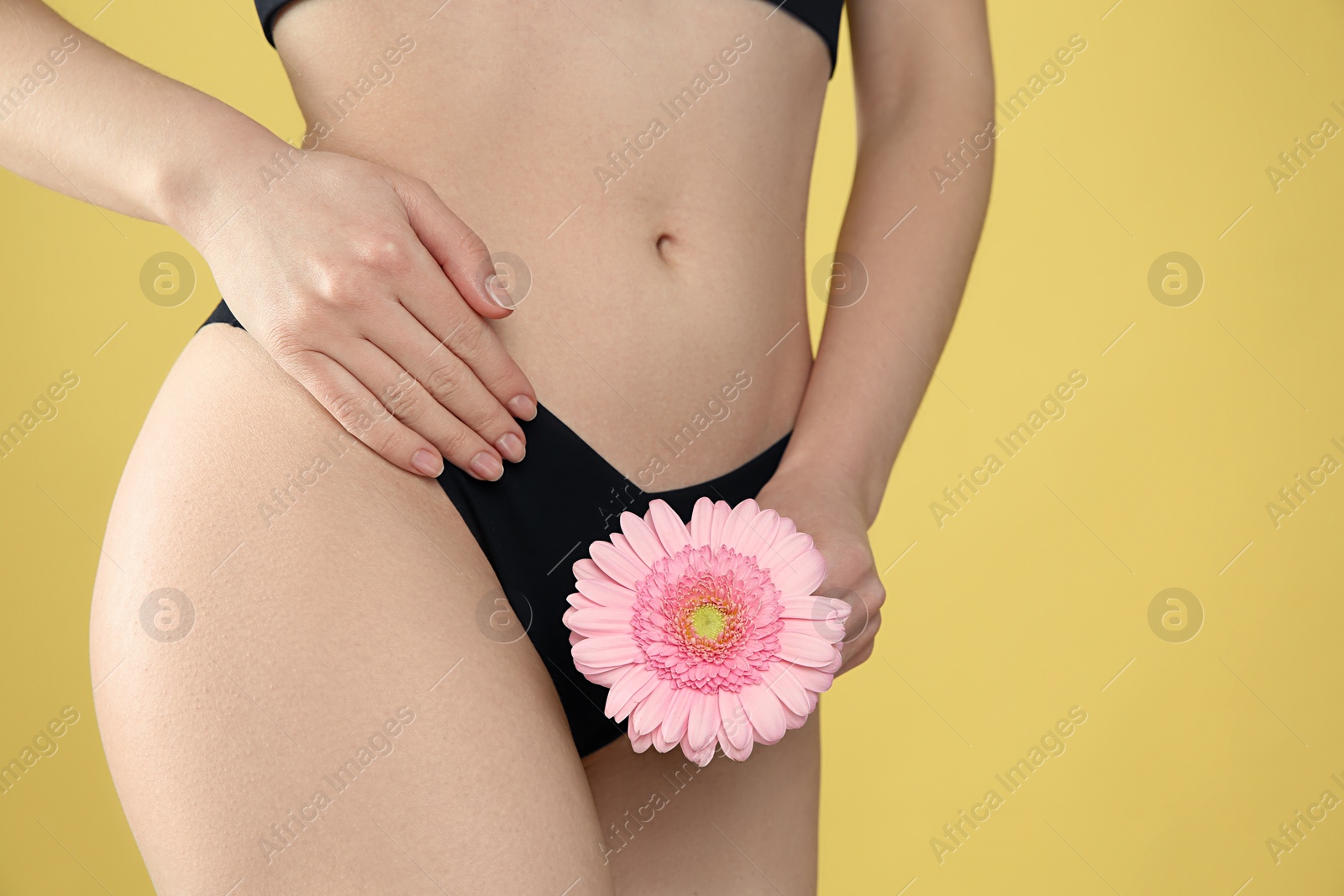 Photo of Gynecology. Woman in underwear with gerbera flower on yellow background, closeup