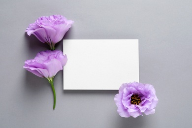Photo of Beautiful Eustoma flowers and card on gray background