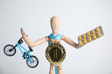 Photo of Sportsman model with medal, bike and pills on white background. Using doping in cycling sport concept