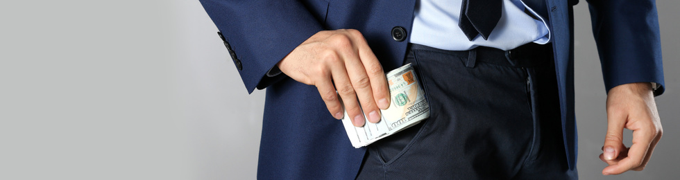 Image of Man putting bribe into pocket on grey background, closeup. Banner design