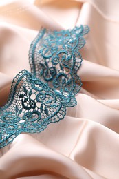 Photo of Beautiful green lace on beige fabric, closeup
