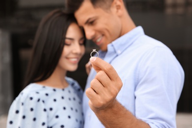 Photo of Lovely couple showing beautiful engagement ring outdoors, focus on hand