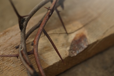 Photo of Crown of thorns and wooden plank on ground, closeup. Easter attribute