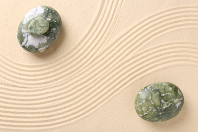 Photo of Zen concept. Stones and pattern on beige sand, flat lay. Space for text