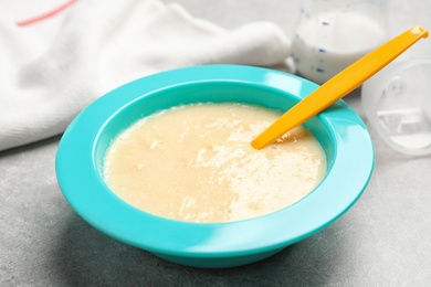Photo of Healthy baby food in bowl on grey table, closeup