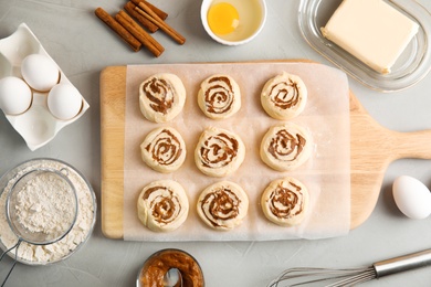 Photo of Flat lay composition with raw cinnamon rolls on grey background