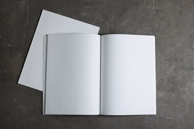 Photo of Open notebook with blank paper sheets on grey textured background, top view. Mockup for design