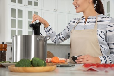 Photo of Woman using thermal immersion circulator in kitchen, closeup. Sous vide cooking