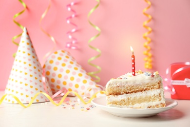 Photo of Slice of delicious birthday cake with candle on table