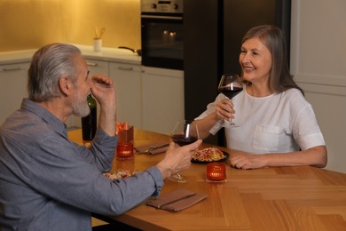 Affectionate senior couple having romantic dinner at home
