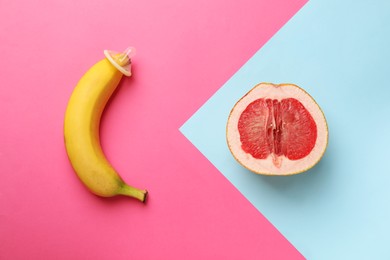 Photo of Banana with condom and half of grapefruit on color background, flat lay. Safe sex concept