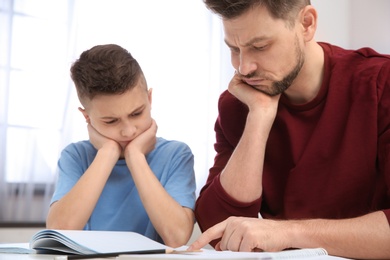 Photo of Dad helping his son with difficult homework assignment in room
