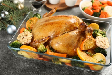 Photo of Delicious chicken with oranges and vegetables on grey table, closeup