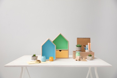 Photo of Composition with house shaped shelves and jars of paints on white table. Interior elements