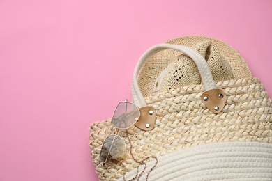 Photo of Elegant woman's straw bag with hat and sunglasses on pink background, top view. Space for text