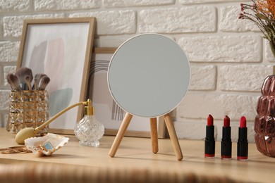 Photo of Mirror, makeup products, perfume and jewelry on wooden dressing table