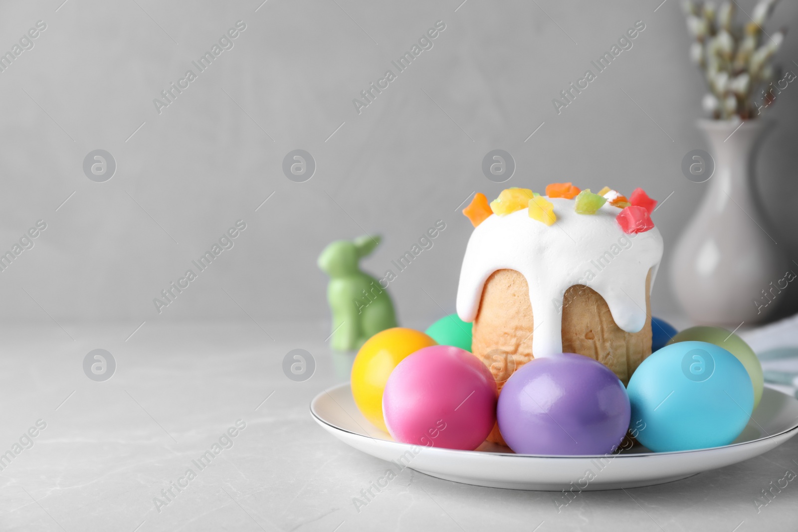 Photo of Beautiful Easter cake and painted eggs on light grey marble table. Space for text