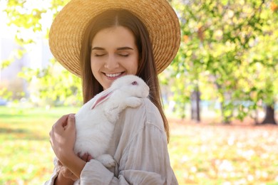 Photo of Happy woman holding cute white rabbit in park