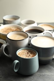 Photo of Many cups of different coffees on slate table