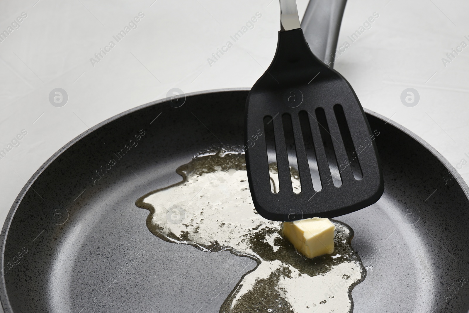 Photo of Frying pan with melting butter and spatula on table, closeup