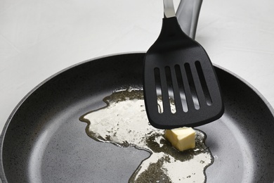 Photo of Frying pan with melting butter and spatula on table, closeup