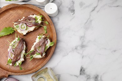Photo of Delicious bruschettas with anchovies, cream cheese, red onion and greens on white marble table, flat lay. Space for text
