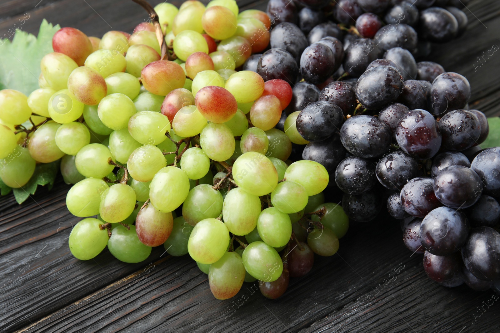 Photo of Different fresh ripe juicy grapes on wooden table, closeup