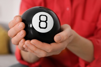 Photo of Woman holding magic eight ball indoors, closeup