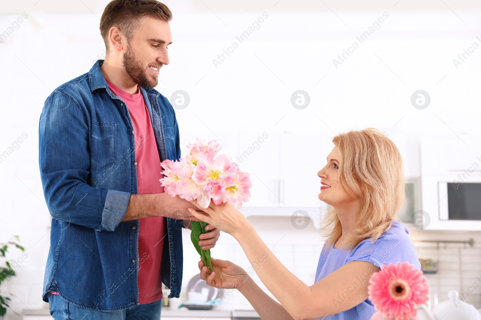 Photo of Young man congratulating his mature mom in kitchen. Happy Mother's Day