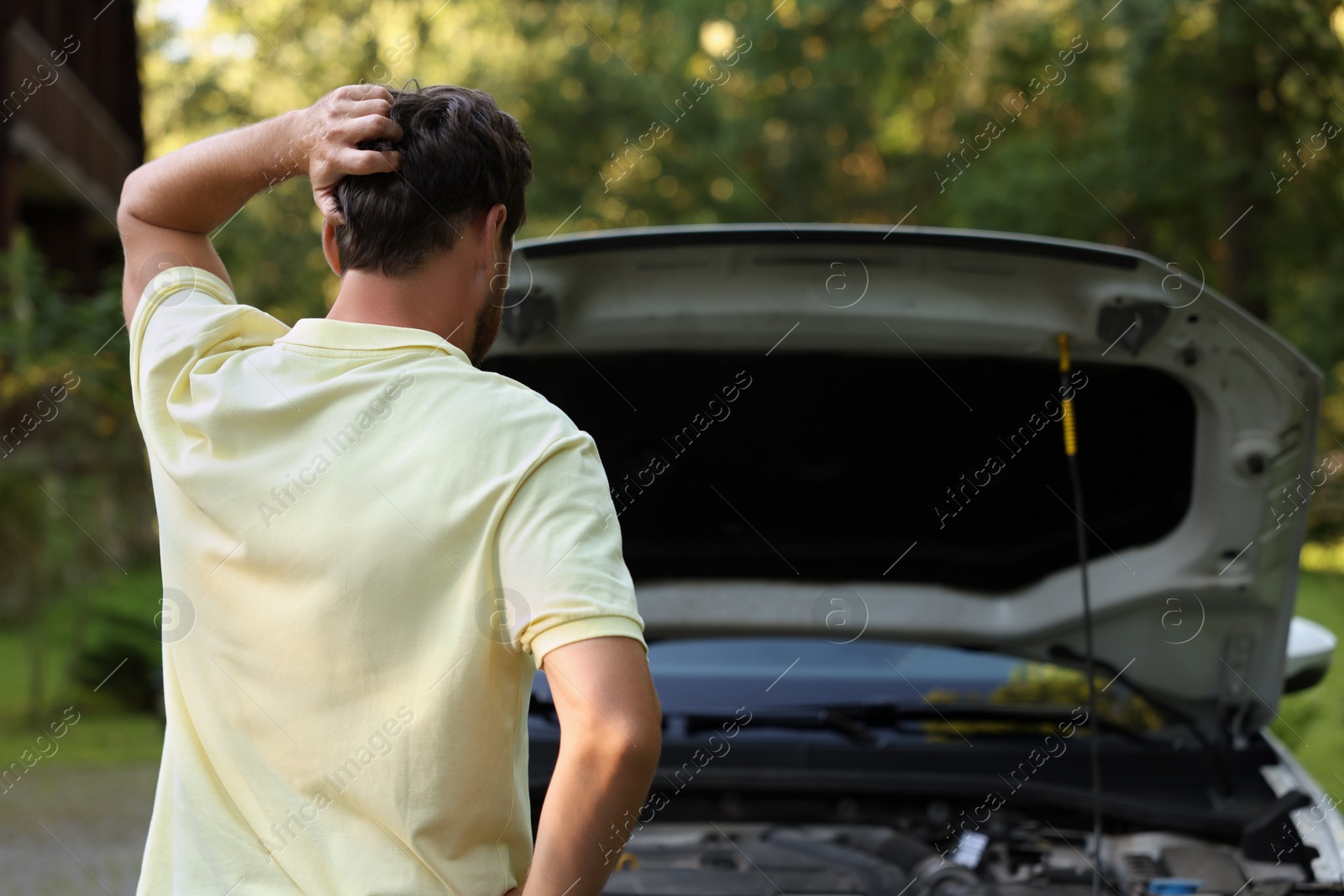 Photo of Man looking under hood of broken car outdoors