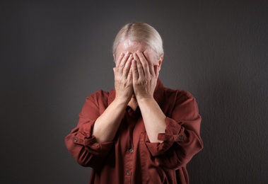 Mature woman suffering from depression on grey background