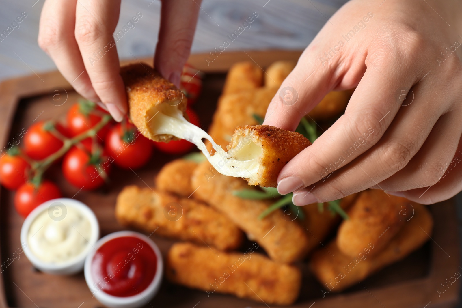 Photo of Woman holding broken cheese stick over board, closeup