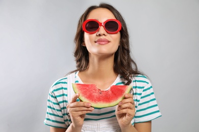 Beautiful young woman with watermelon on grey background