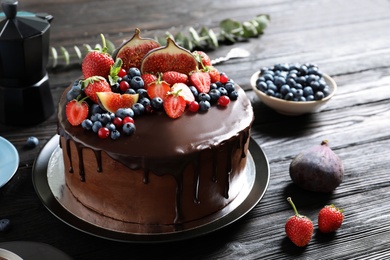 Photo of Fresh delicious homemade chocolate cake with berries on dark table