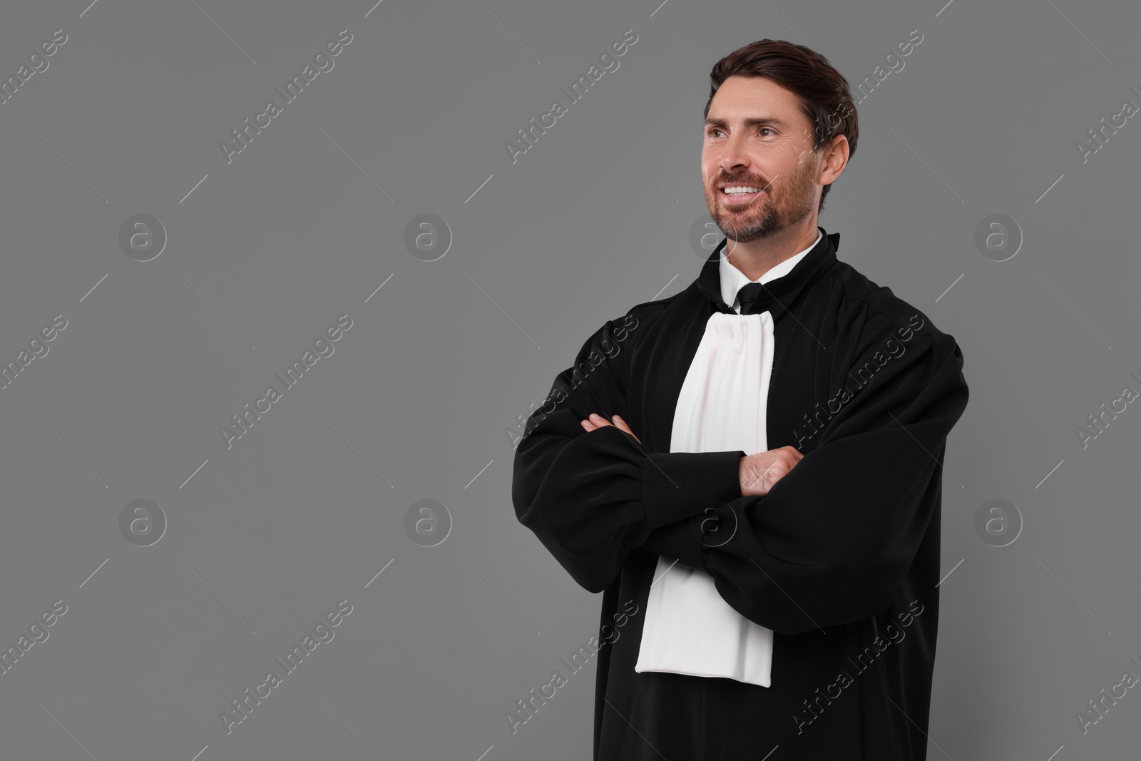 Photo of Smiling judge with crossed arms on grey background. Space for text