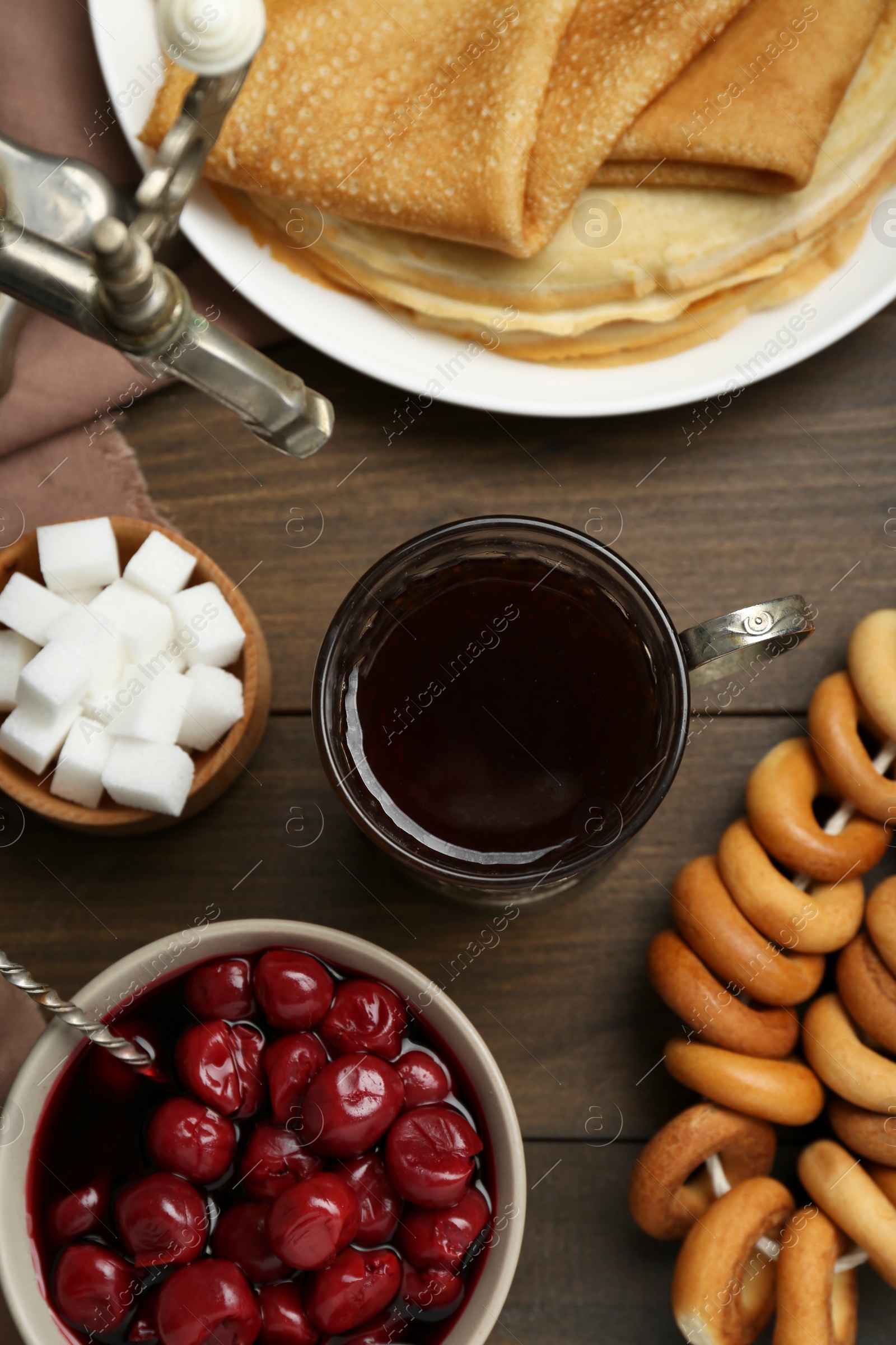 Photo of Metal samovar with cup of tea and treats on wooden table, flat lay