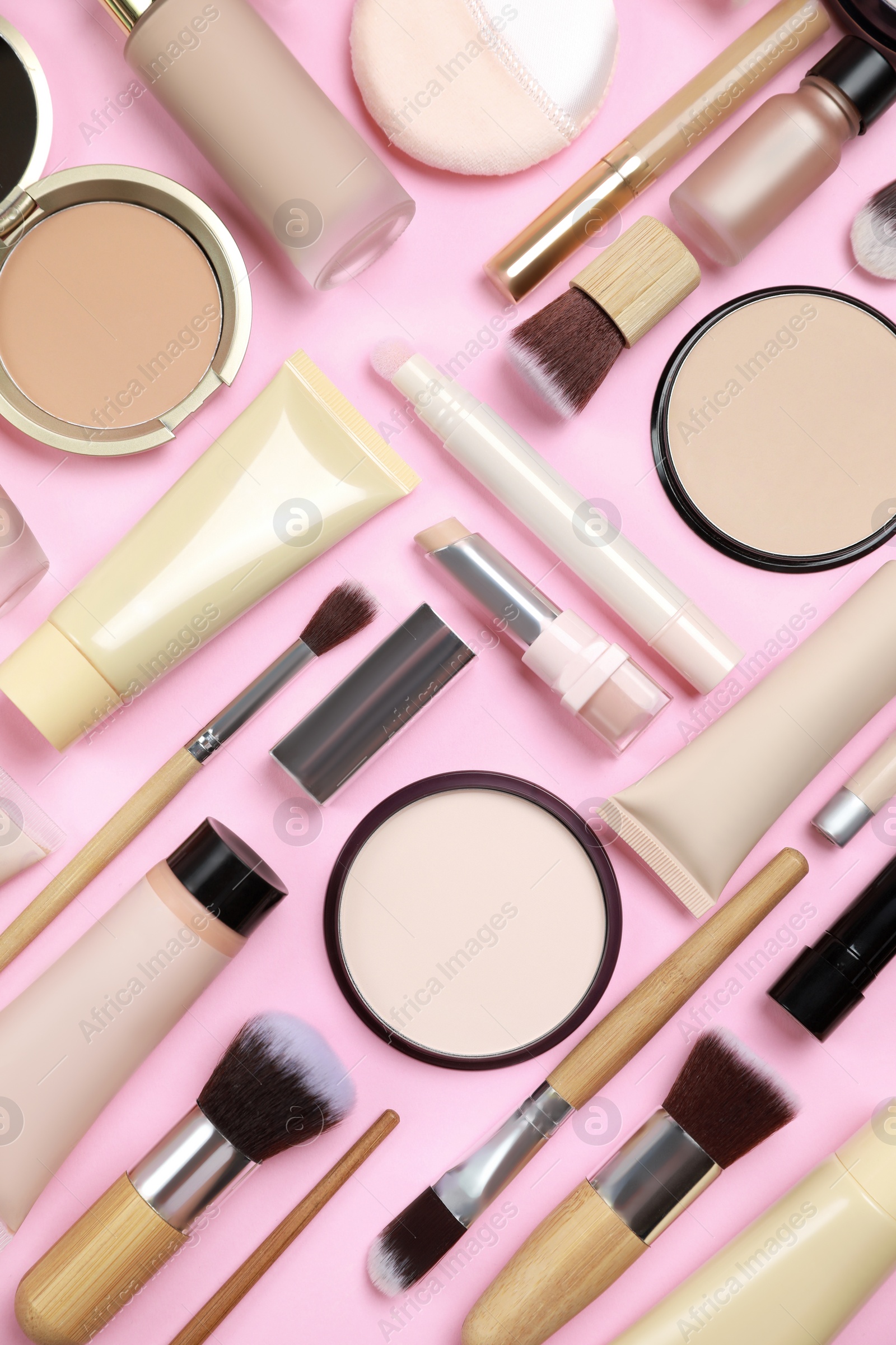 Photo of Face powders and other decorative cosmetic products on pink background, flat lay