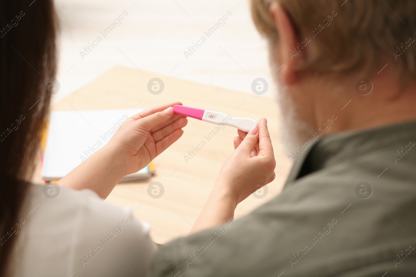 Photo of Daughter showing her father pregnancy test indoors, closeup. Grandparents' reaction to future grandson