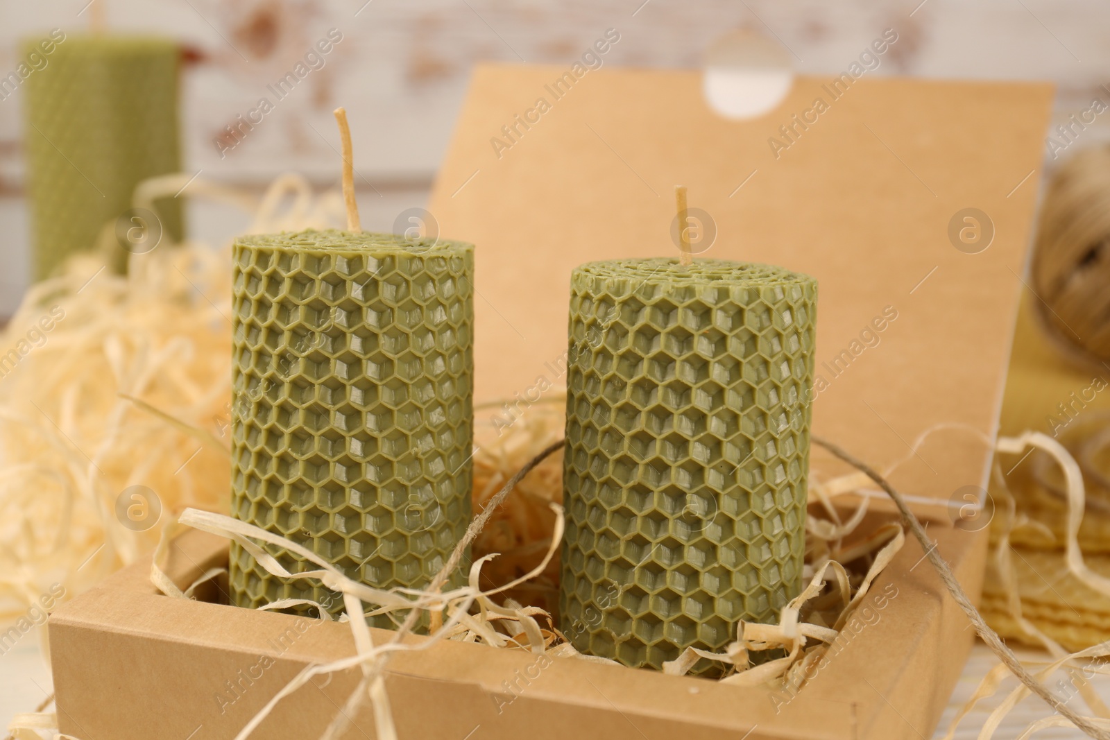 Photo of Stylish elegant beeswax candles and jute twine on white wooden table