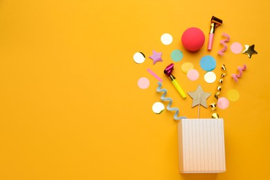 Flat lay composition with party items and box on orange background, space for text