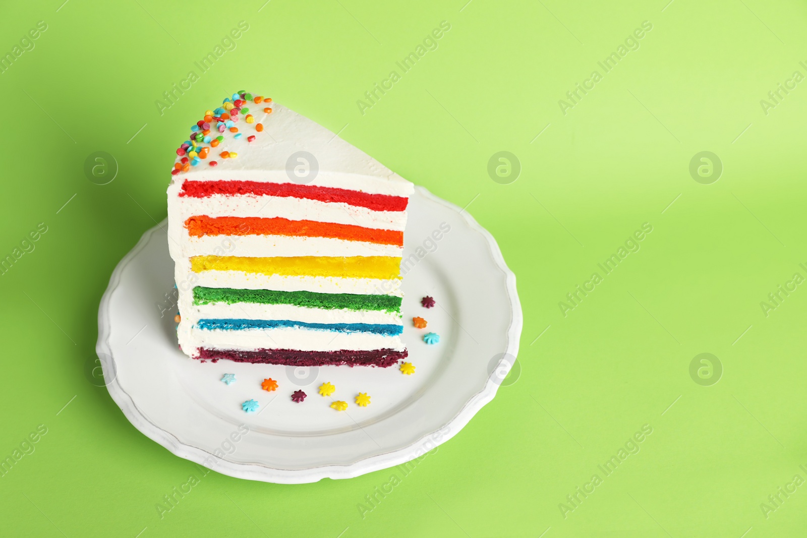 Photo of Slice of delicious rainbow cake on color background